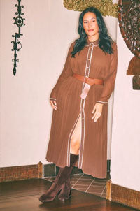 woman in dress leaning against door wearing sangeti knee high boots
