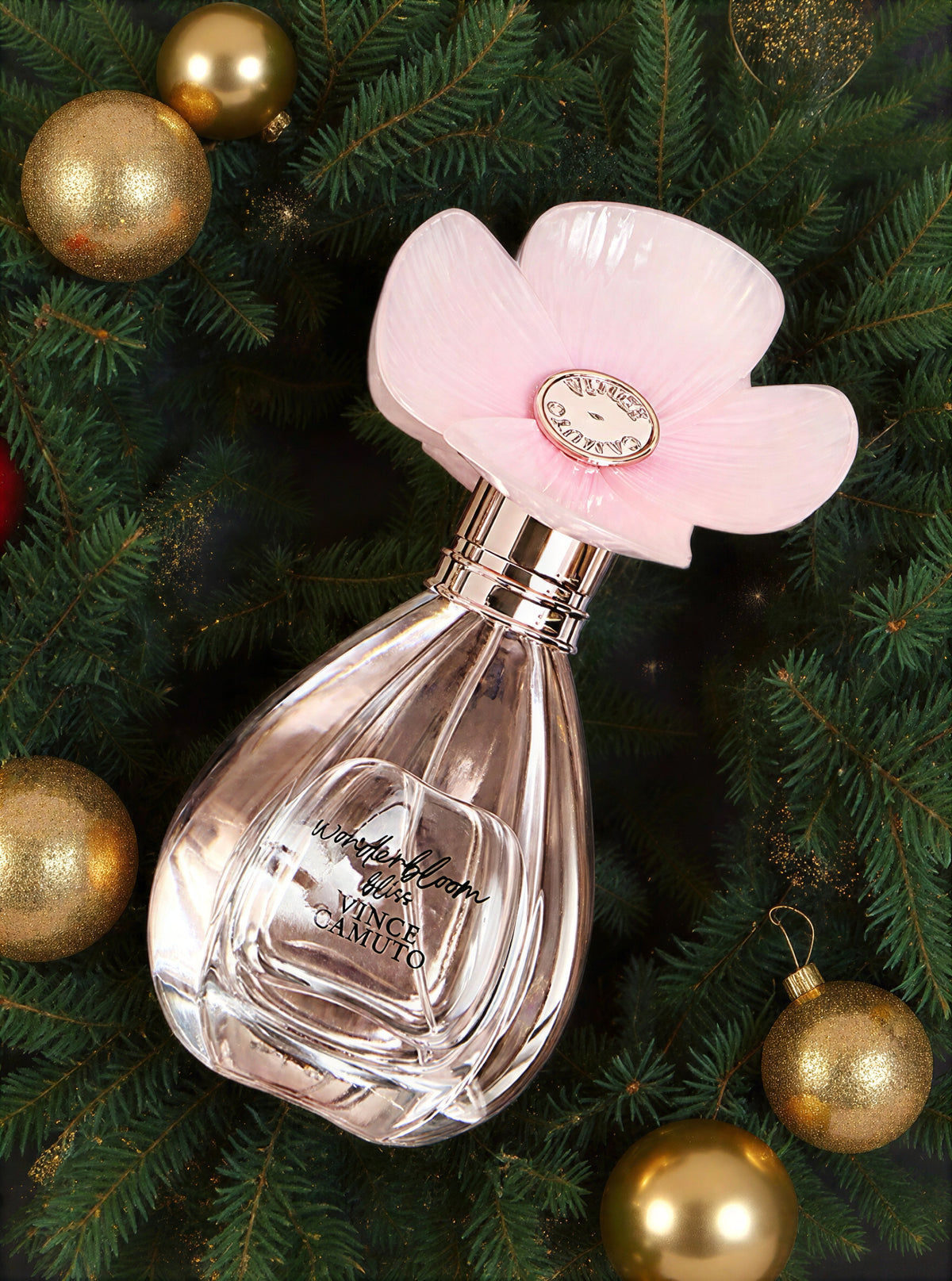 wonderbloom perfume with a pink flower top sitting on green garland 