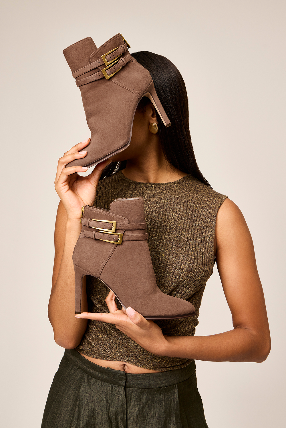 woman holding up a pair of the Sahra Bootie in Toasted Taupe 